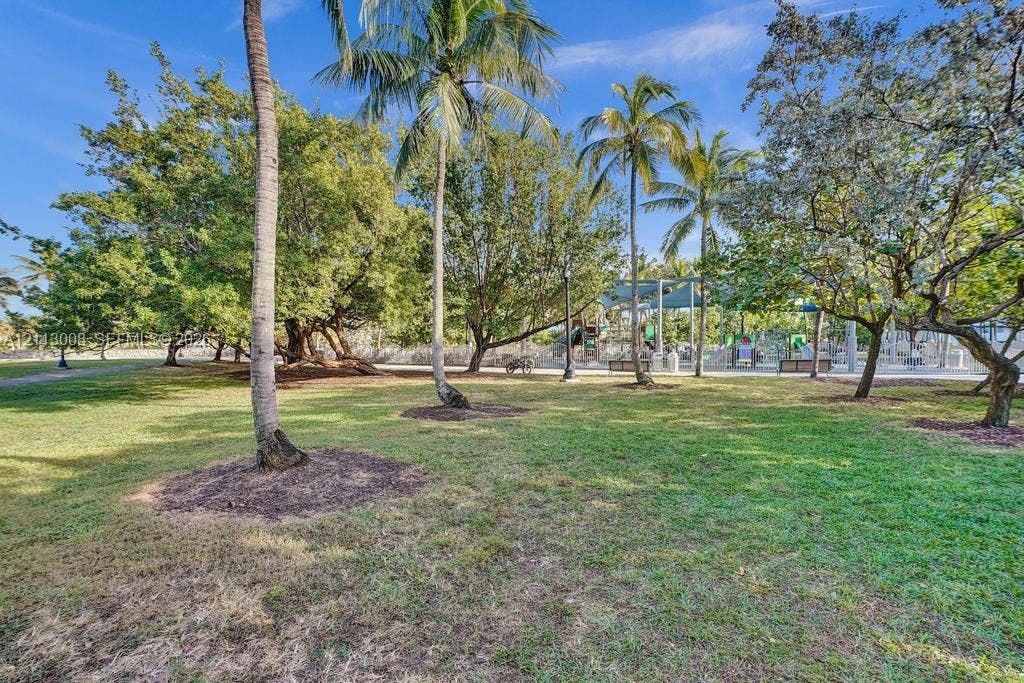Expansive green space featuring mature trees and established palms