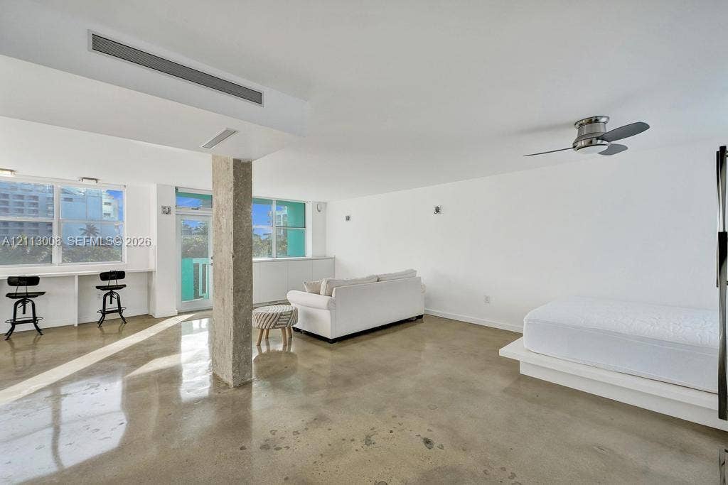 Polished concrete flooring, exposed concrete structural column, built-in desk counter, recessed lighting, and ceiling-mounted fan