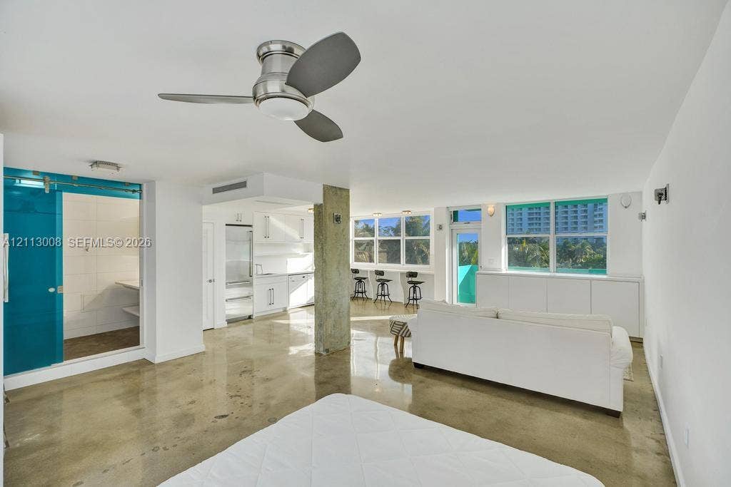 Open-concept interior featuring polished concrete flooring, exposed concrete support column, and floor-to-ceiling windows