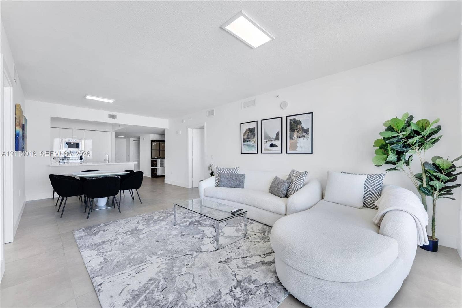 Open-concept interior featuring large-format tile flooring, recessed rectangular lighting fixtures, and clean white walls