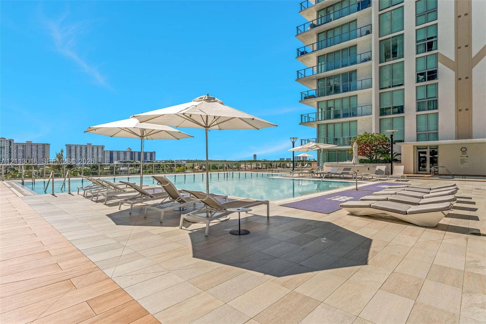 Elevated swimming pool featuring a tiled deck, glass railing, and high-rise exterior architecture