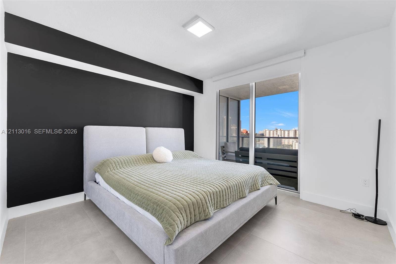Room featuring an accent wall, large sliding glass door, private balcony, neutral-toned flooring, and square ceiling-mounted lighting