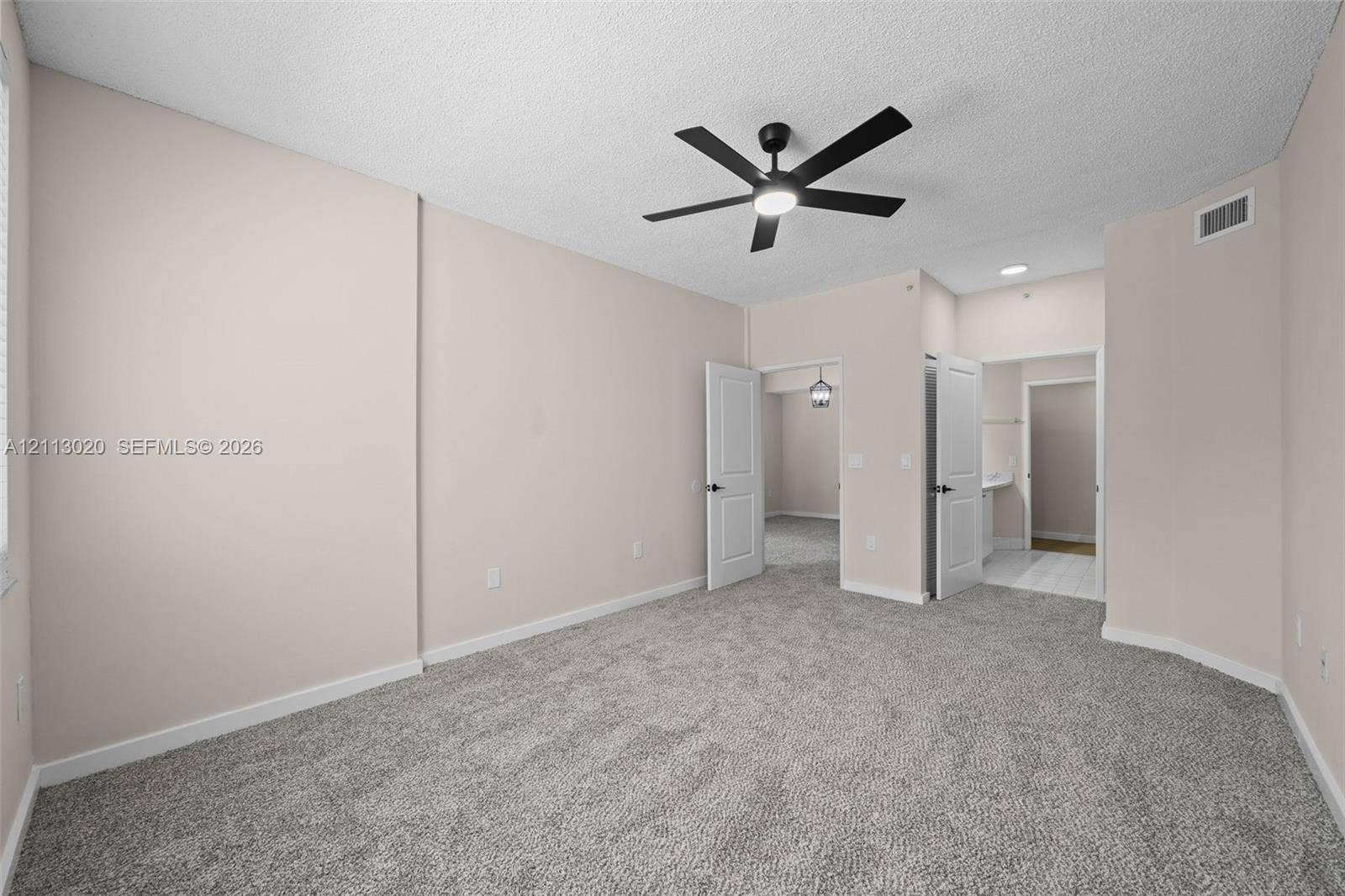 6968 SW 39th Street, #F104, Davie, Davie, FL 33314 Neutral-toned interior space featuring textured carpeted flooring, a ceiling fan with integrated lighting, and white six-panel interior doors