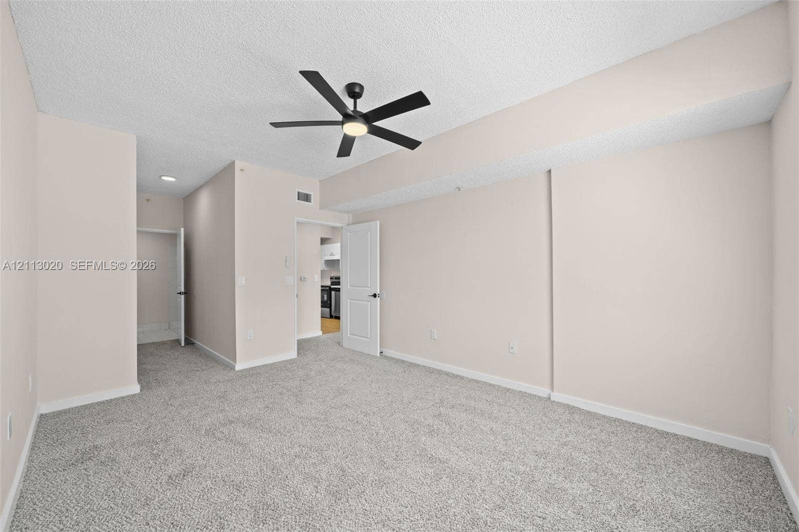 6968 SW 39th Street, #F104, Davie, Davie, FL 33314 Neutral-toned interior space featuring wall-to-wall carpeting, a multi-blade ceiling fan with integrated lighting, and white paneled doors