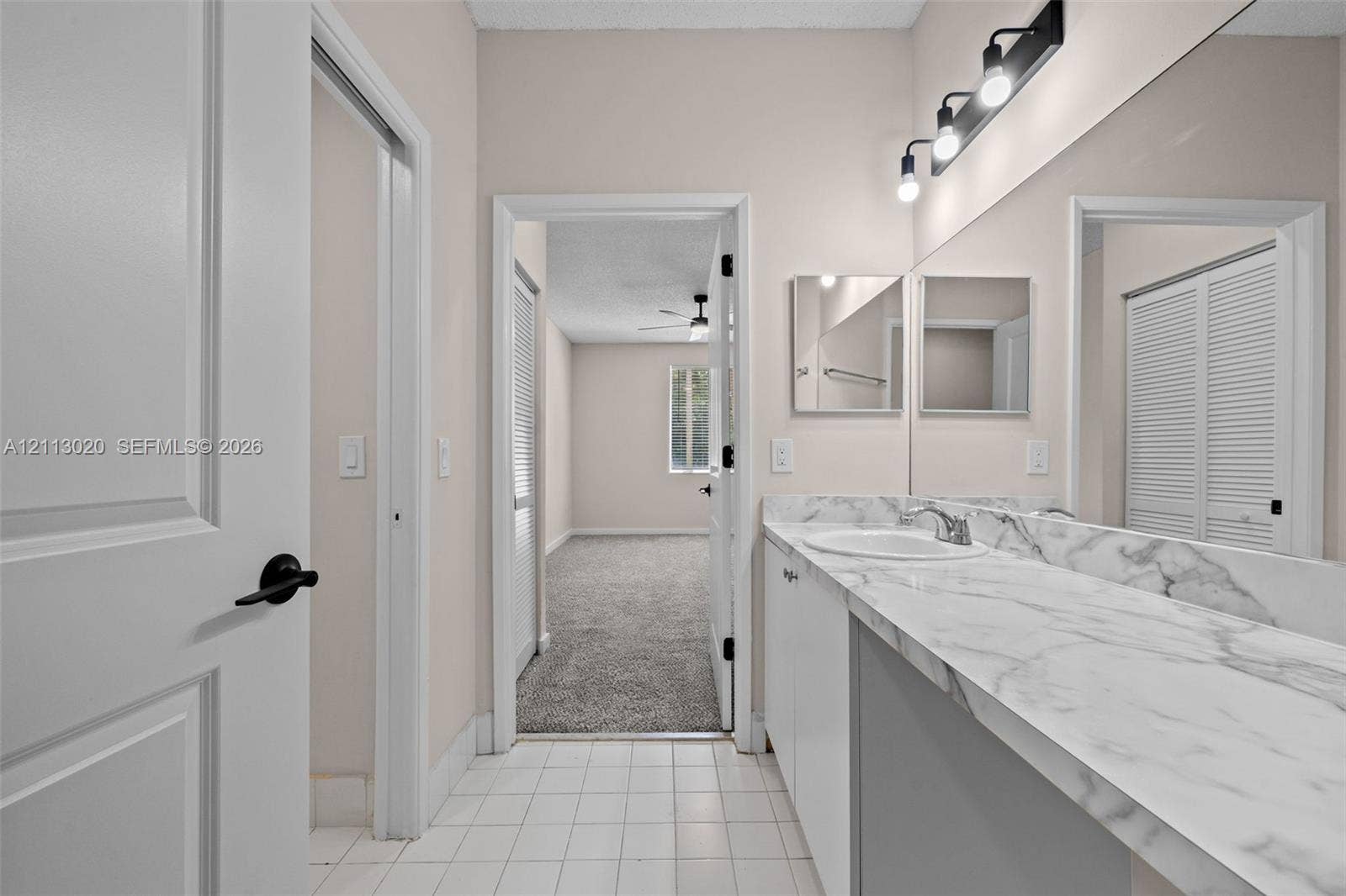 6968 SW 39th Street, #F104, Davie, Davie, FL 33314 Bathroom featuring a white vanity with stone-finish countertop, undermount sink, full-width mirror, and multi-bulb vanity lighting