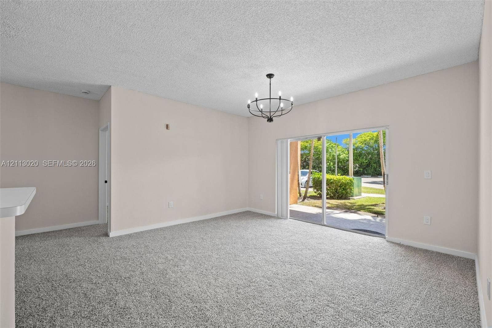 6968 SW 39th Street, #F104, Davie, Davie, FL 33314 Neutral-toned interior featuring carpeting, a metal multi-light chandelier, and sliding glass doors