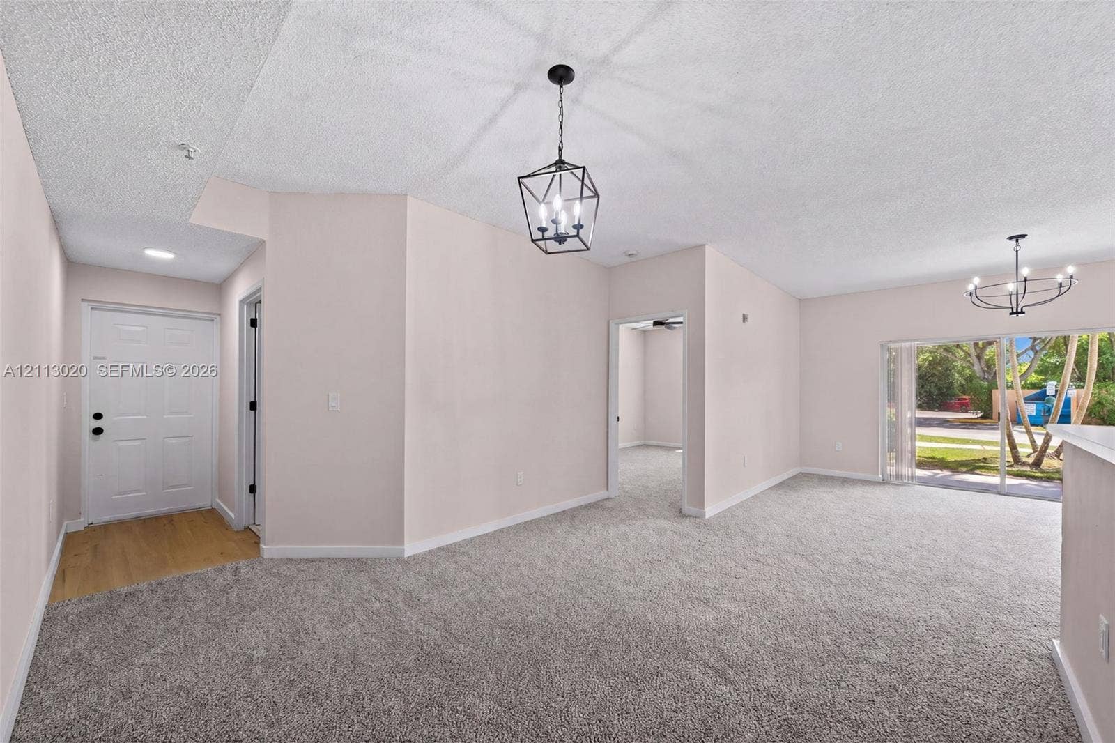 6968 SW 39th Street, #F104, Davie, Davie, FL 33314 Interior space featuring neutral wall tones, wall-to-wall carpeting, metal geometric pendant lighting, and sliding glass doors with exterior access