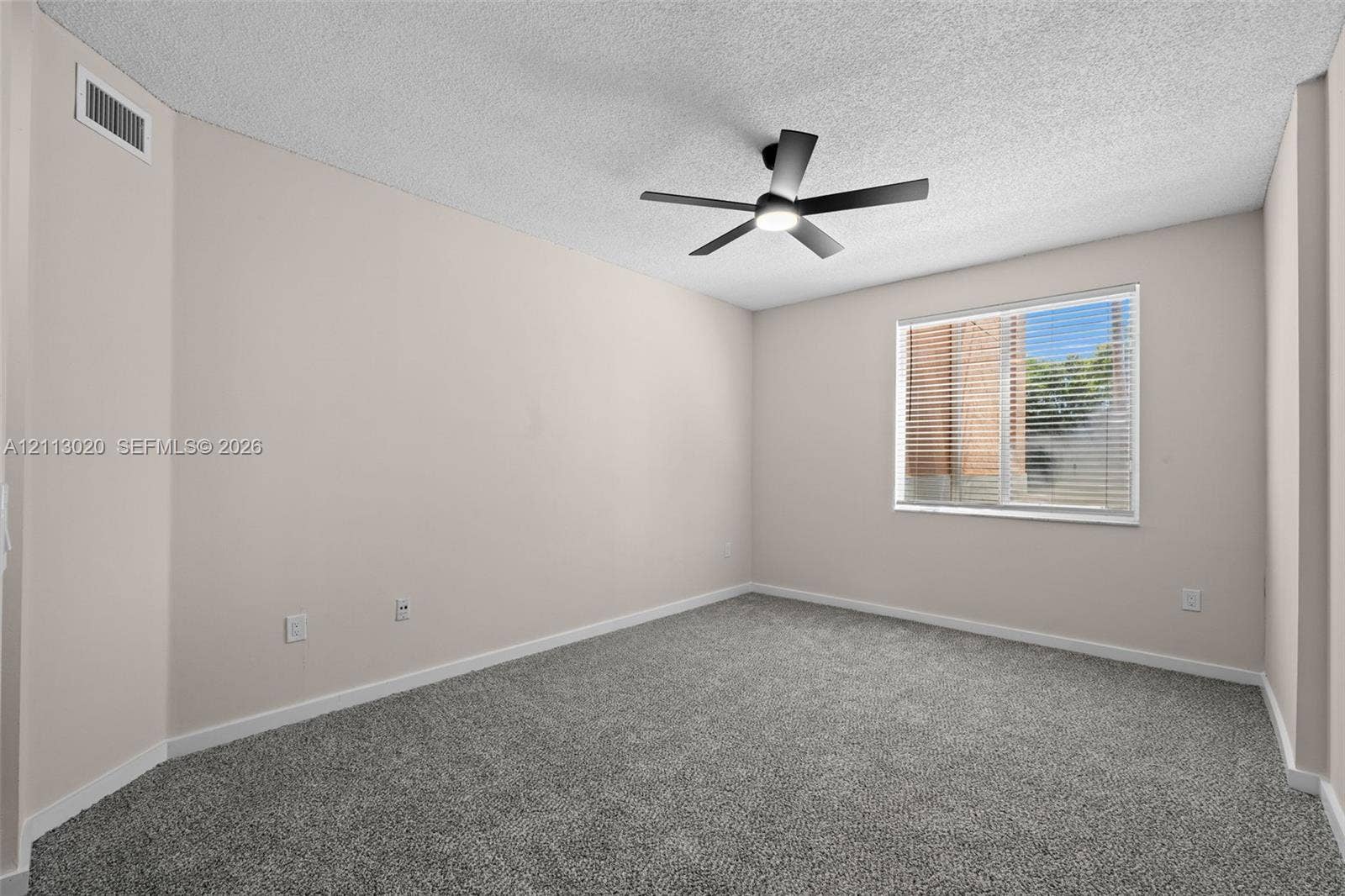 6968 SW 39th Street, #F104, Davie, Davie, FL 33314 Room featuring neutral wall tones, gray carpeting, a textured ceiling, and a ceiling-mounted light fixture with a fan