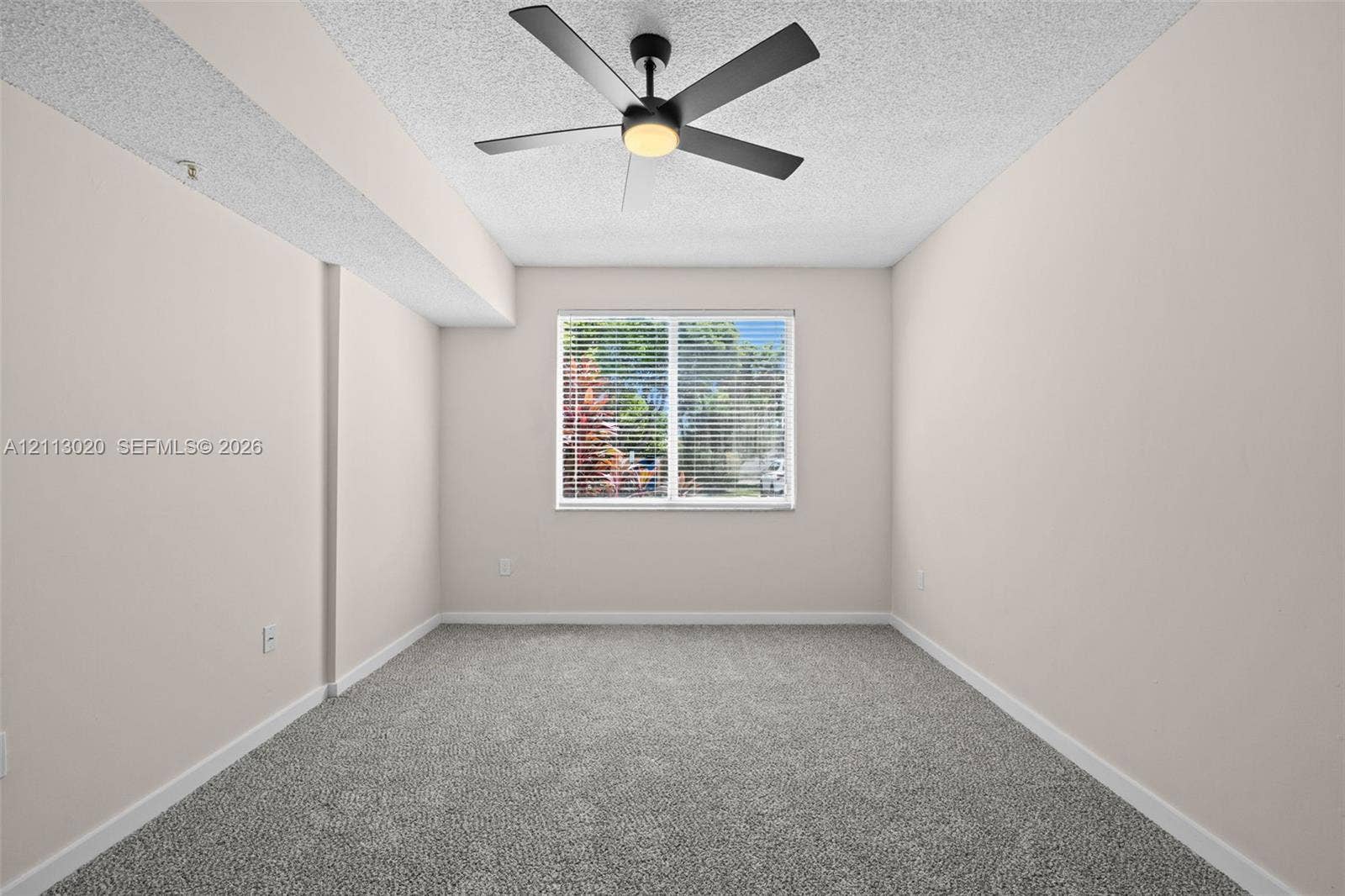 6968 SW 39th Street, #F104, Davie, Davie, FL 33314 Neutral-toned interior featuring wall-to-wall carpeting, a multi-blade ceiling fan with integrated lighting, and a single-pane window with horizontal blinds