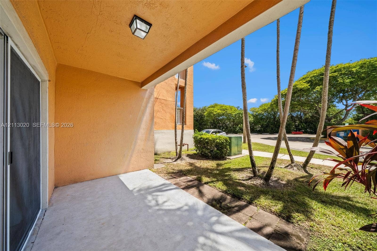 6968 SW 39th Street, #F104, Davie, Davie, FL 33314 Covered ground-level patio with concrete flooring, stucco exterior wall, and wall-mounted light fixture