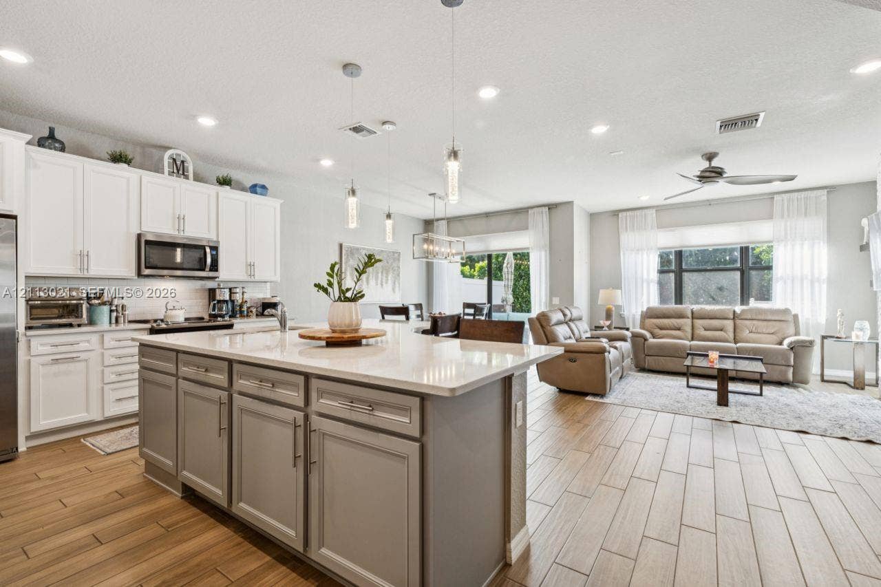 8228 Tailshot Court, Lake Worth, Lake Worth, FL 33467 Kitchen featuring an expansive center island with stone-finish countertops, ceiling-mounted pendant lighting, shaker-style cabinetry, and wood-finish flooring