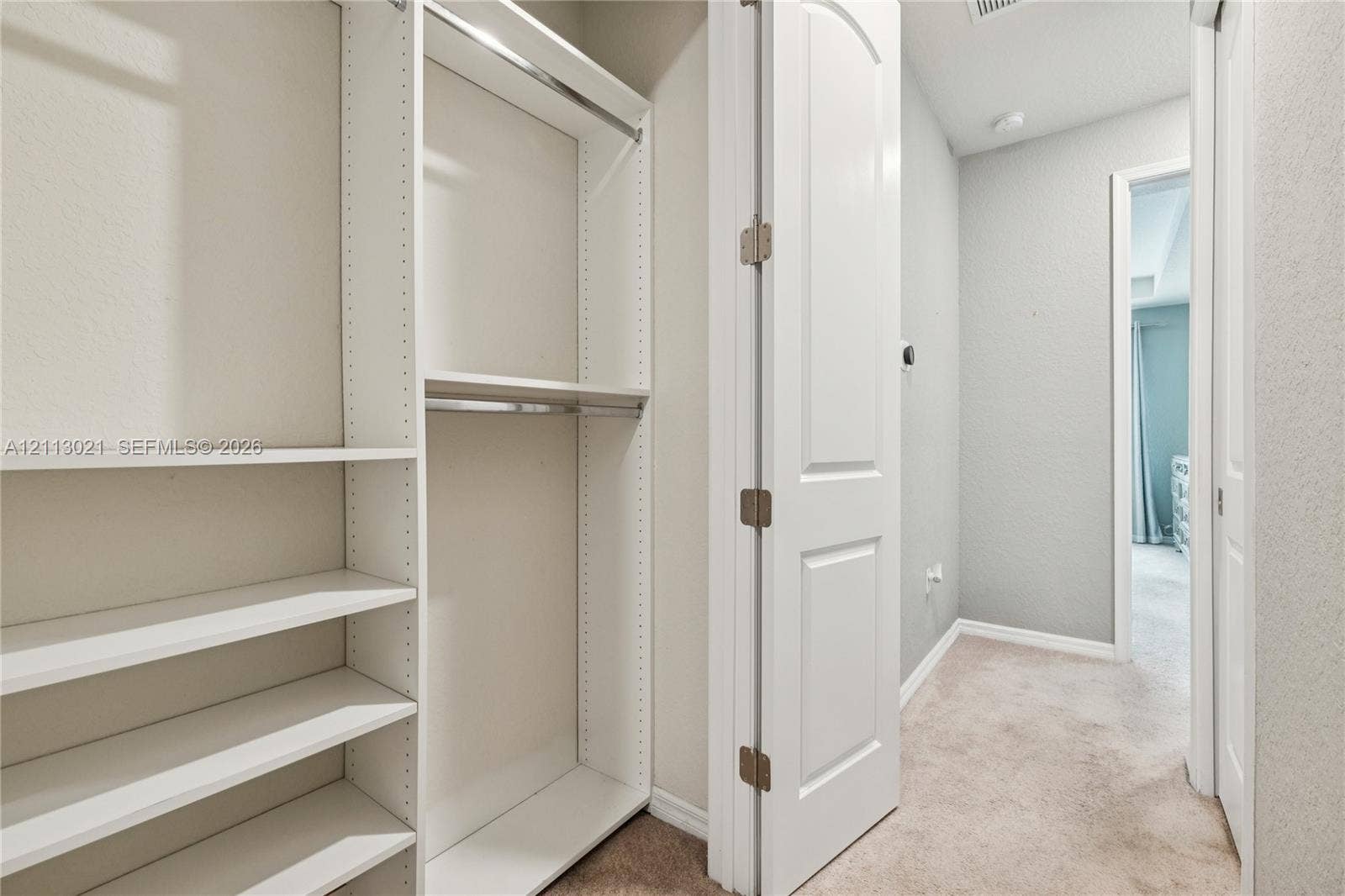 8228 Tailshot Court, Lake Worth, Lake Worth, FL 33467 Built-in white storage shelving, dual hanging rods, and a solid-core interior door