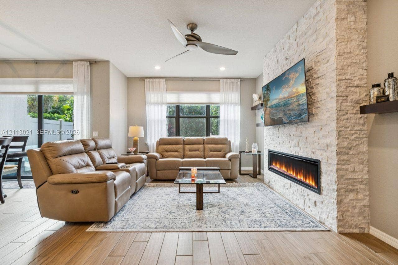 8228 Tailshot Court, Lake Worth, Lake Worth, FL 33467 Living area featuring wood-finish tile flooring, recessed lighting, ceiling fan, and a floor-to-ceiling stone-veneer accent wall with an integrated linear electric fireplace