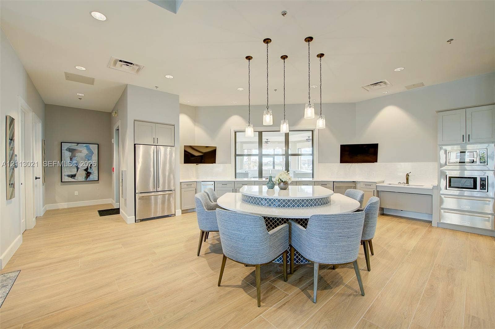 8228 Tailshot Court, Lake Worth, Lake Worth, FL 33467 Kitchen featuring wood-finish flooring, stainless steel appliances, built-in wall ovens, and a circular island with stone-finish countertops and decorative tile detailing