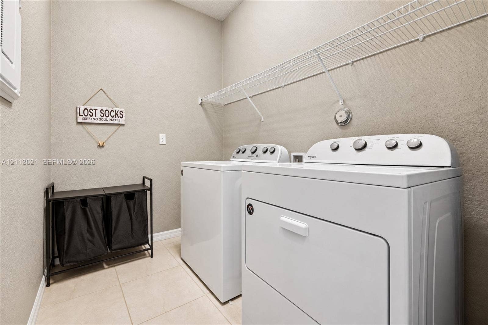 8228 Tailshot Court, Lake Worth, Lake Worth, FL 33467 Laundry area featuring neutral-toned tile flooring, textured wall finishes, and integrated white wire shelving