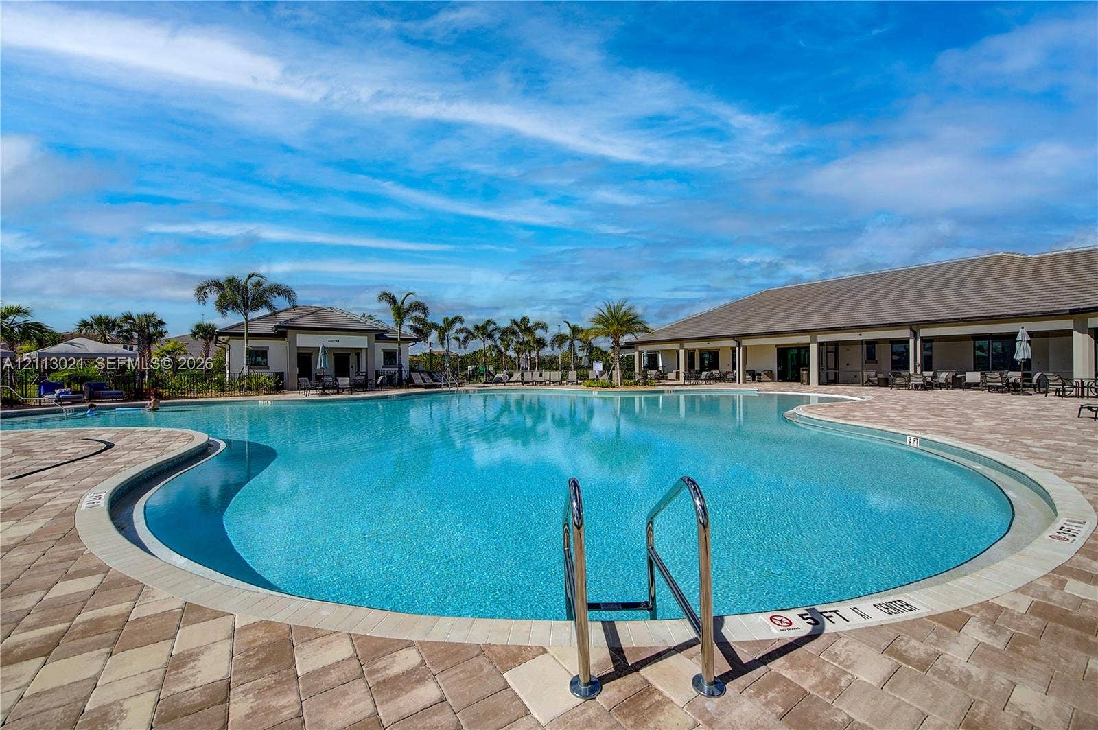 8228 Tailshot Court, Lake Worth, Lake Worth, FL 33467 Swimming pool with concrete paver decking, metal entry rails, and surrounding palm trees