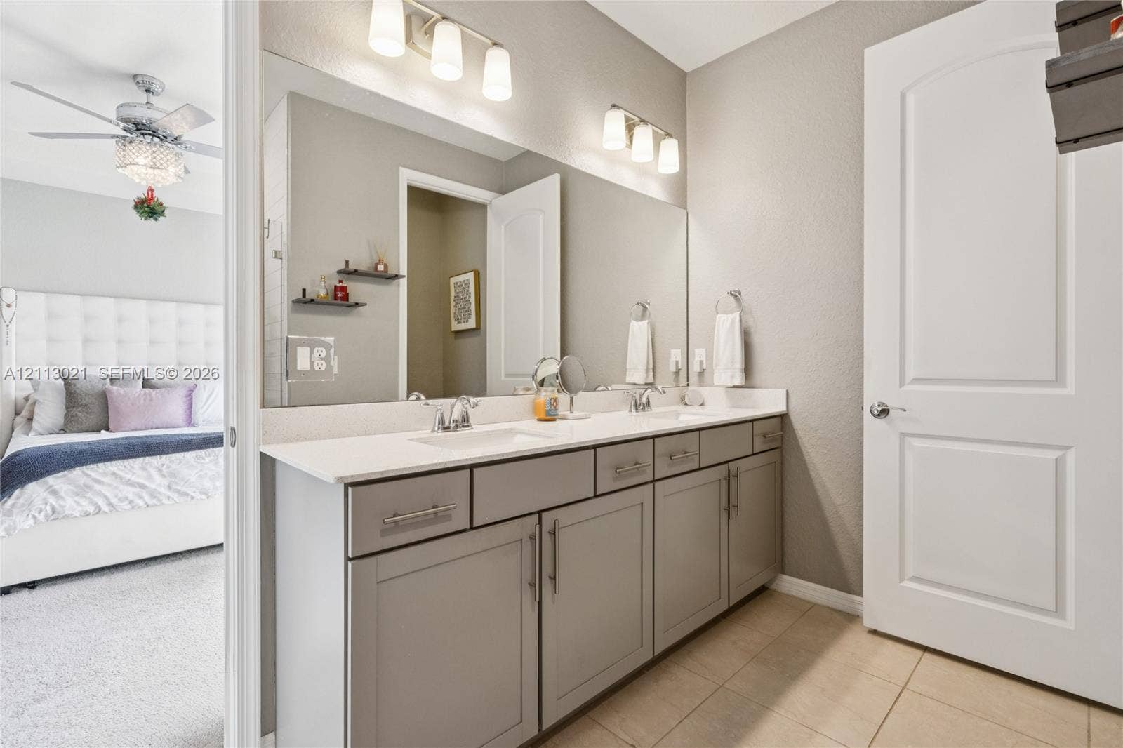 8228 Tailshot Court, Lake Worth, Lake Worth, FL 33467 Dual-sink vanity with a solid surface countertop, shaker-style cabinetry, two wall-mounted light fixtures, and a large-format mirror