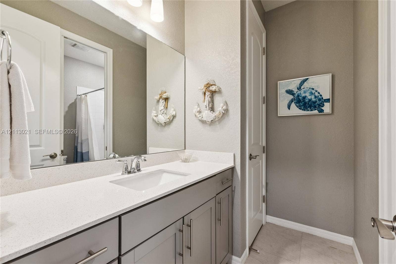 8228 Tailshot Court, Lake Worth, Lake Worth, FL 33467 Vanity featuring a stone-composite countertop, undermount sink, and shaker-style cabinetry with polished metal hardware, complemented by a large wall-mounted mirror and integrated lighting