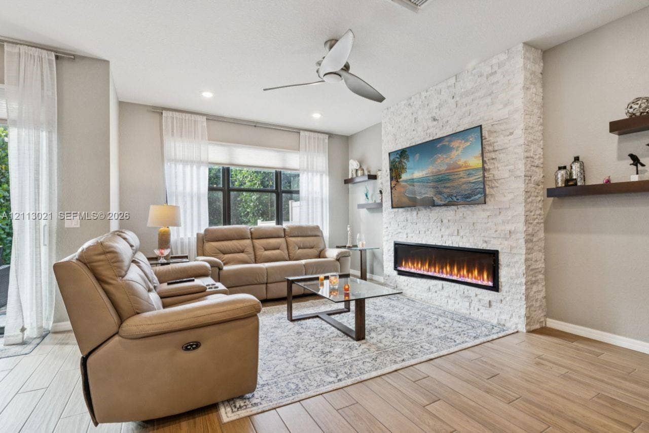 8228 Tailshot Court, Lake Worth, Lake Worth, FL 33467 Living area featuring a floor-to-ceiling white stone fireplace surround, modern linear electric fireplace, wood-finish flooring, recessed lighting, and floating wall shelves