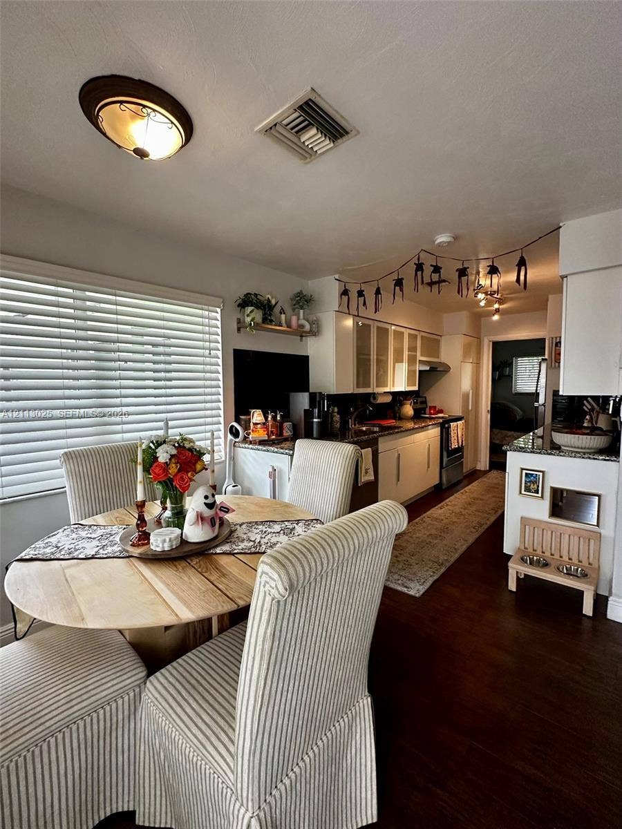 Kitchen featuring shaker-style cabinetry, stone countertops, dark wood-finish flooring, and horizontal window blinds