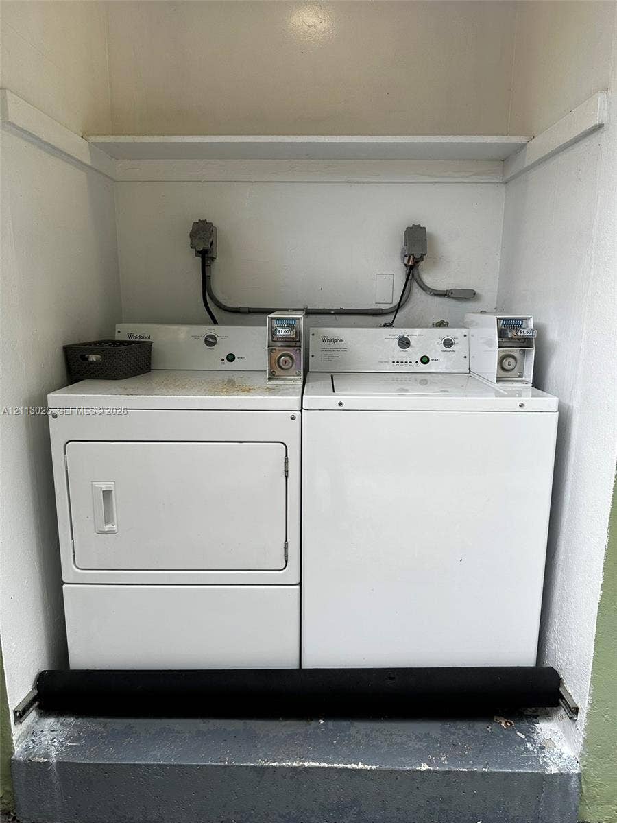 Laundry area featuring a side-by-side coin-operated washer and dryer set with an overhead built-in storage shelf