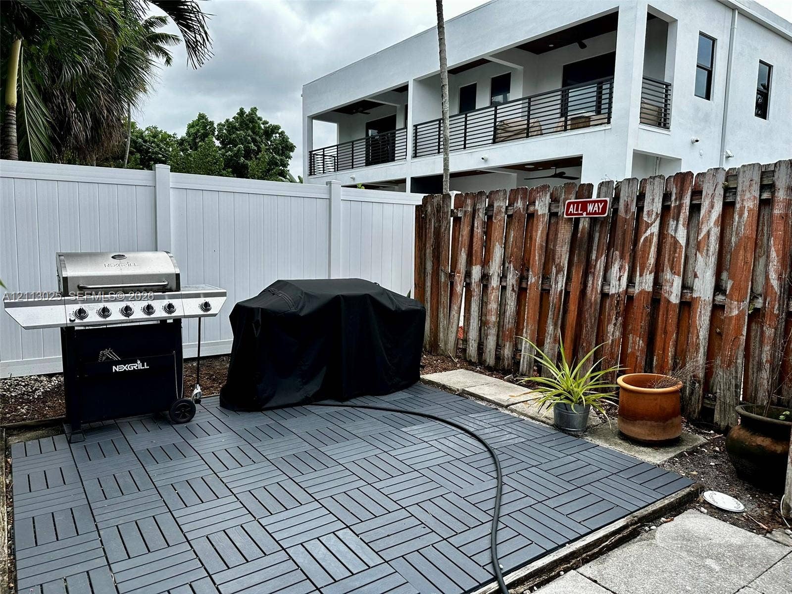 Private outdoor area featuring interlocking deck tiles, enclosed by a combination of white vinyl and wood privacy fencing