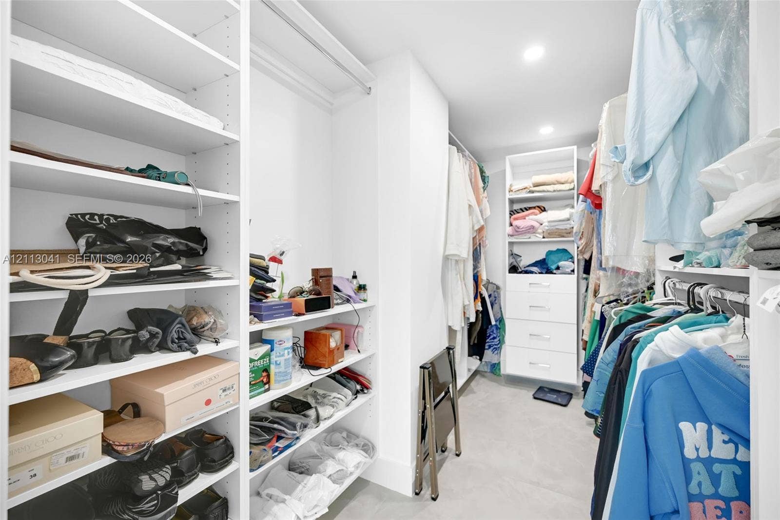 7135 Collins Avenue, #1426, Miami Beach, FL 33141 Custom walk-in closet featuring extensive white built-in shelving, multiple hanging rods, and integrated storage drawers with minimalist hardware