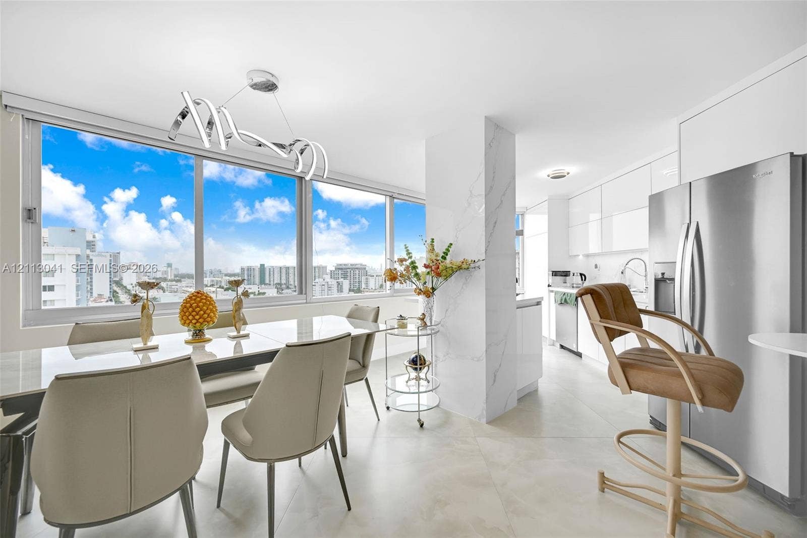 7135 Collins Avenue, #1426, Miami Beach, FL 33141 Floor-to-ceiling windows featuring urban scenery, large-format tile flooring, a stone-cladding structural column, custom high-gloss cabinetry, and a contemporary architectural pendant light fixture