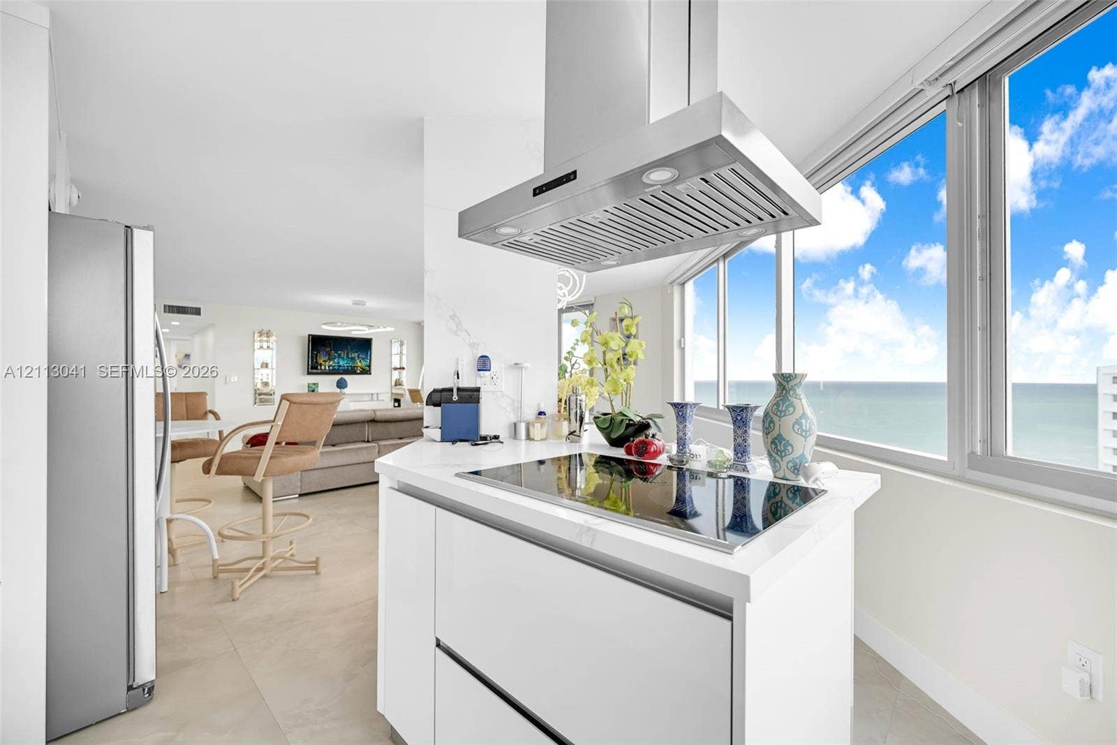 7135 Collins Avenue, #1426, Miami Beach, FL 33141 Kitchen featuring white cabinetry, solid-surface countertop, stainless steel range hood, built-in cooktop, and floor-to-ceiling windows