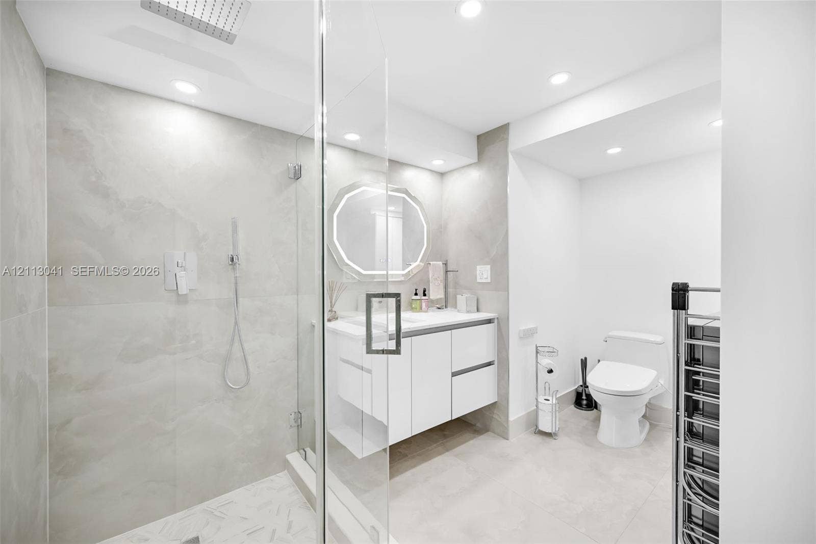 7135 Collins Avenue, #1426, Miami Beach, FL 33141 Walk-in shower with floor-to-ceiling stone-finish tile, rainfall shower head, glass enclosure, floating vanity, and recessed lighting