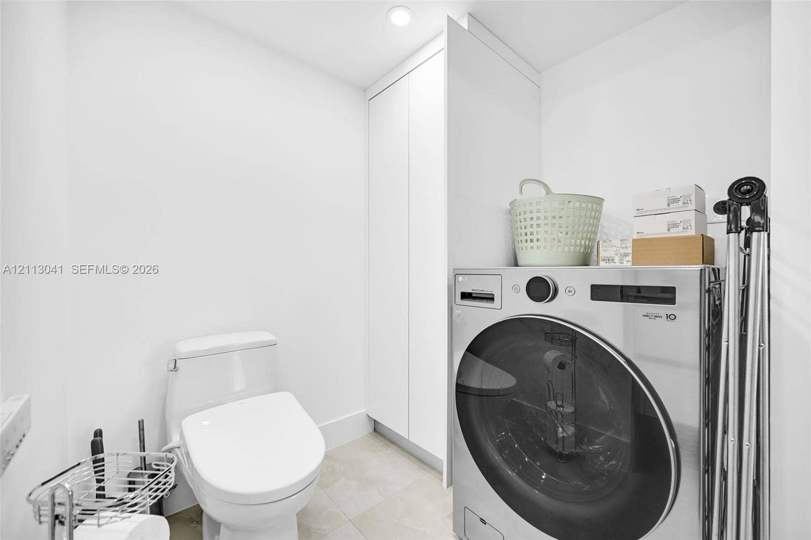 7135 Collins Avenue, #1426, Miami Beach, FL 33141 Compact room featuring a floor-to-ceiling white storage cabinet, a sleek one-piece toilet, and tile flooring