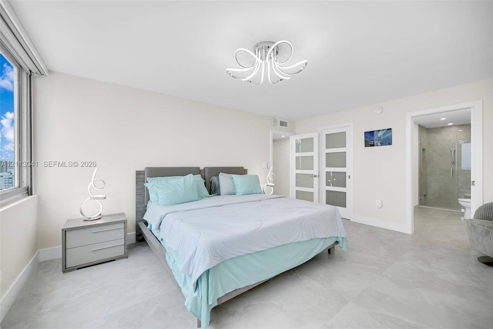 7135 Collins Avenue, #1426, Miami Beach, FL 33141 Neutral-toned tile flooring, contemporary multi-arm flush-mount lighting, large-format window, and dual white-framed doors with frosted glass inserts