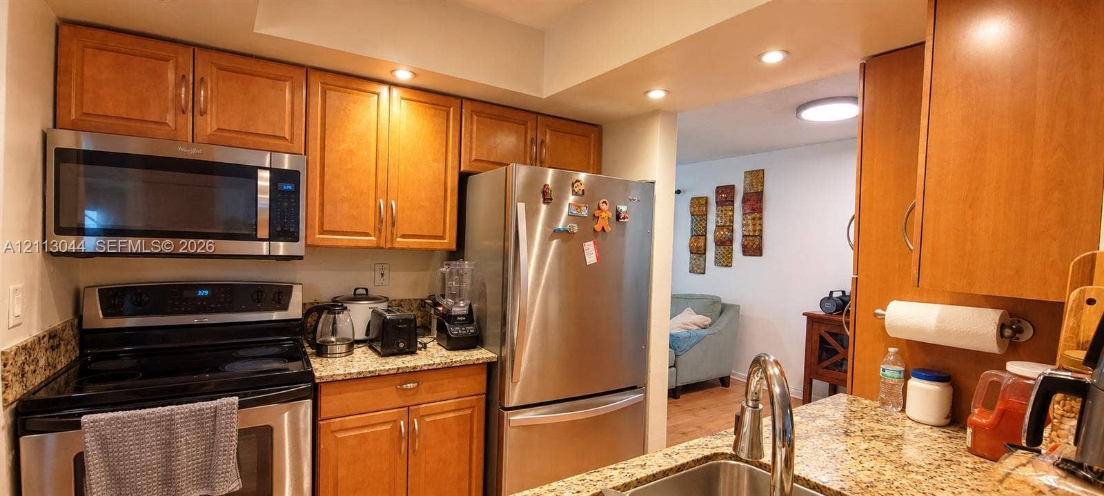 6735 NW 62nd Street, Tamarac, FL 33321 Kitchen featuring stone-finish countertops, stainless steel appliances, custom wood-finish cabinetry, and recessed lighting