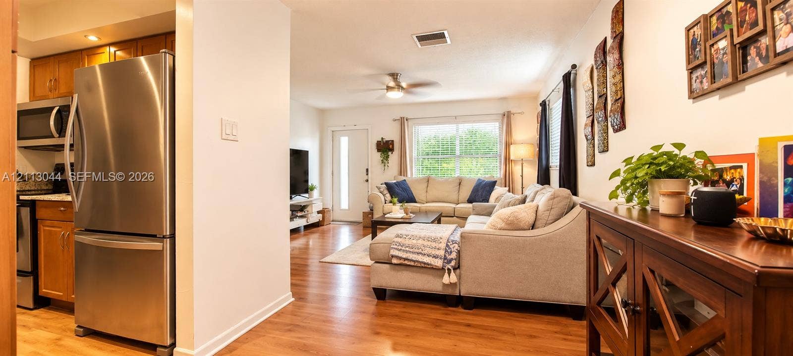 6735 NW 62nd Street, Tamarac, FL 33321 Kitchen featuring stainless steel refrigerator and microwave, wood-finish flooring, and ceiling fan