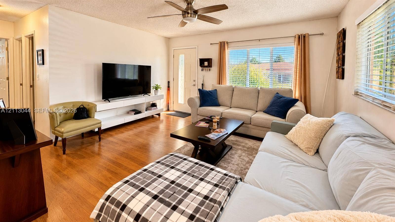 6735 NW 62nd Street, Tamarac, FL 33321 Living area featuring wood-finish flooring, a ceiling fan, and large windows with horizontal blinds