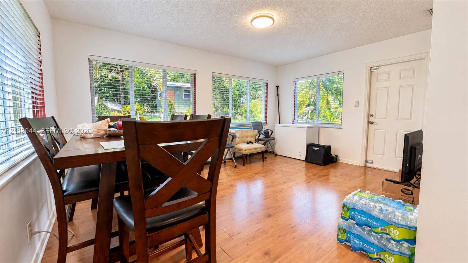 6735 NW 62nd Street, Tamarac, FL 33321 Spacious room featuring wood-finish flooring, large windows with horizontal blinds, and a solid-core entry door