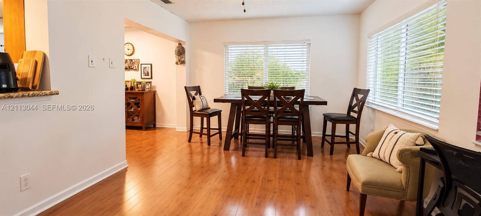 6735 NW 62nd Street, Tamarac, FL 33321 Open-concept dining area featuring wood-finish flooring, dual-aspect windows, and horizontal blinds