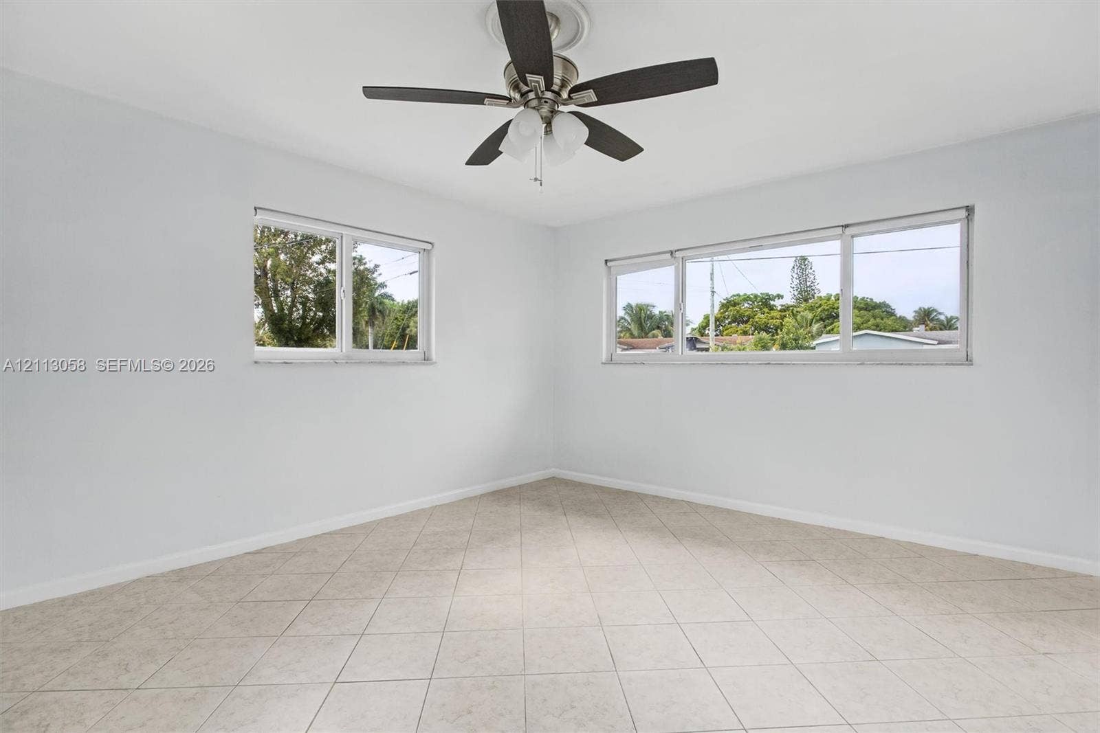 1980 NW 33rd Court, Oakland Park, FL 33309 Neutral-toned tile flooring, multi-pane windows, and a ceiling fan with integrated lighting