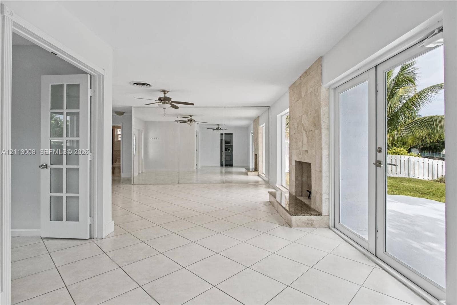 1980 NW 33rd Court, Oakland Park, FL 33309 Tile flooring, floor-to-ceiling mirrored walls, stone-surround fireplace with a hearth, and glass-paned French doors