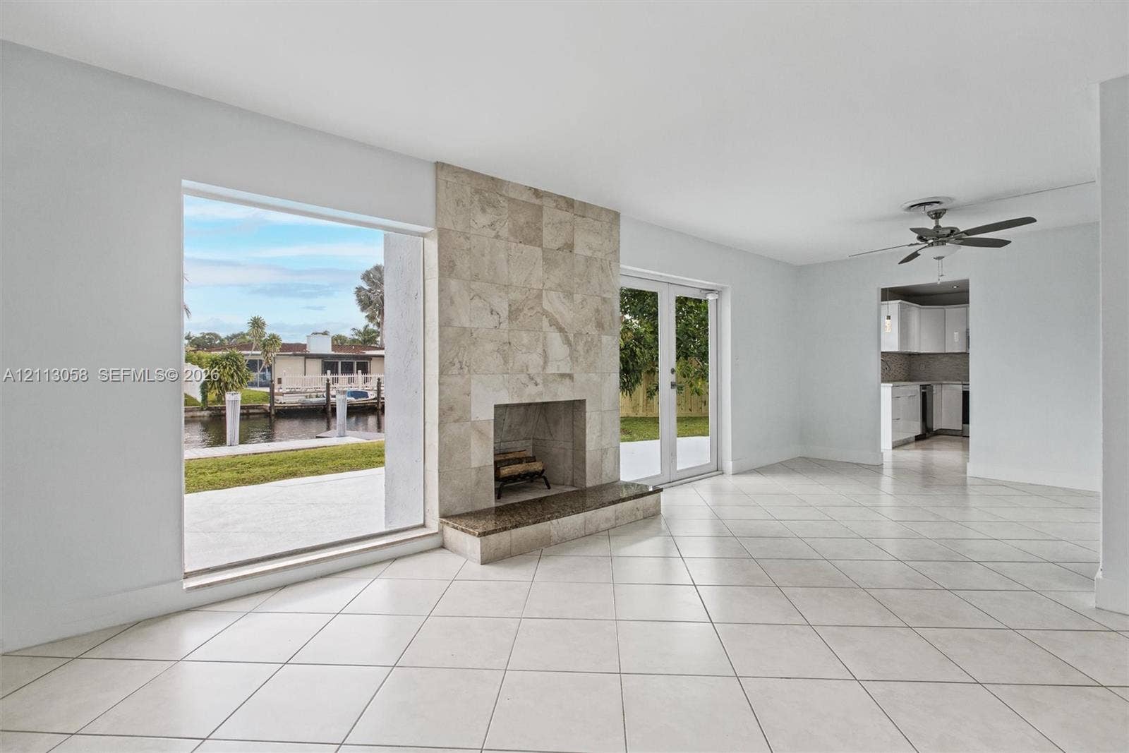 1980 NW 33rd Court, Oakland Park, FL 33309 Living area featuring large-format tile flooring, a floor-to-ceiling fireplace with stone tile surround, a built-in stone hearth, and double glass doors