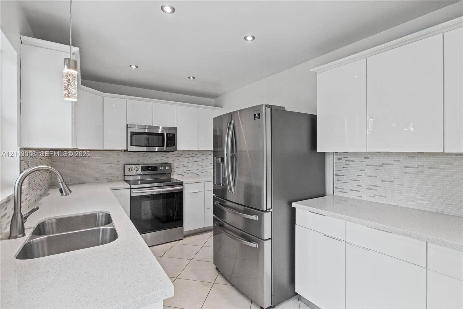1980 NW 33rd Court, Oakland Park, FL 33309 Kitchen featuring white slab-front cabinetry, stone-finish countertops, stainless steel appliances, a mosaic tile backsplash, and recessed ceiling lighting
