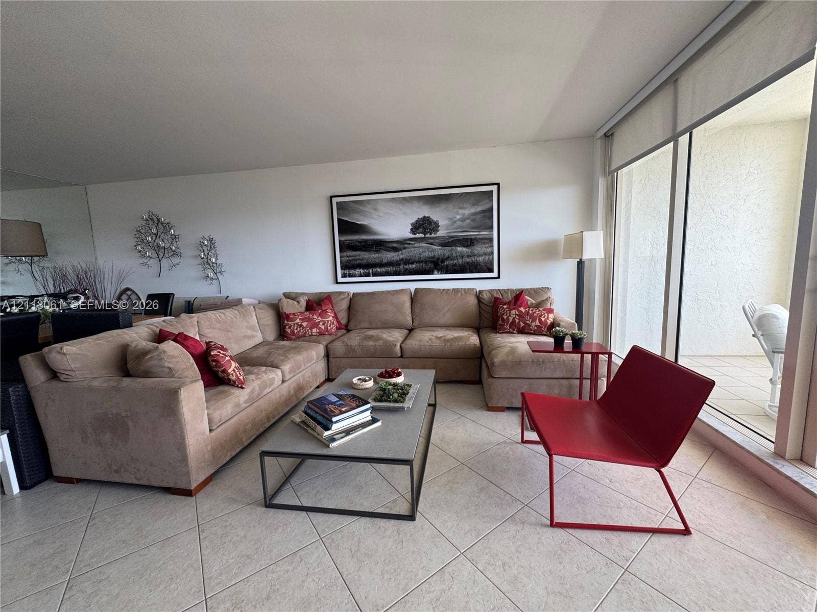 Living area featuring expansive floor-to-ceiling glass doors, neutral tile flooring, and a full-length wall mirror