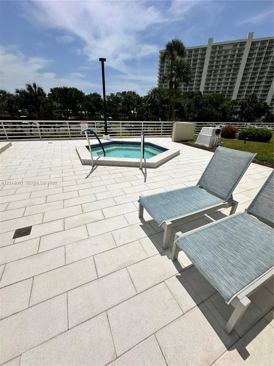 Elevated terrace featuring a paved stone deck, an in-ground spa, and a perimeter safety railing
