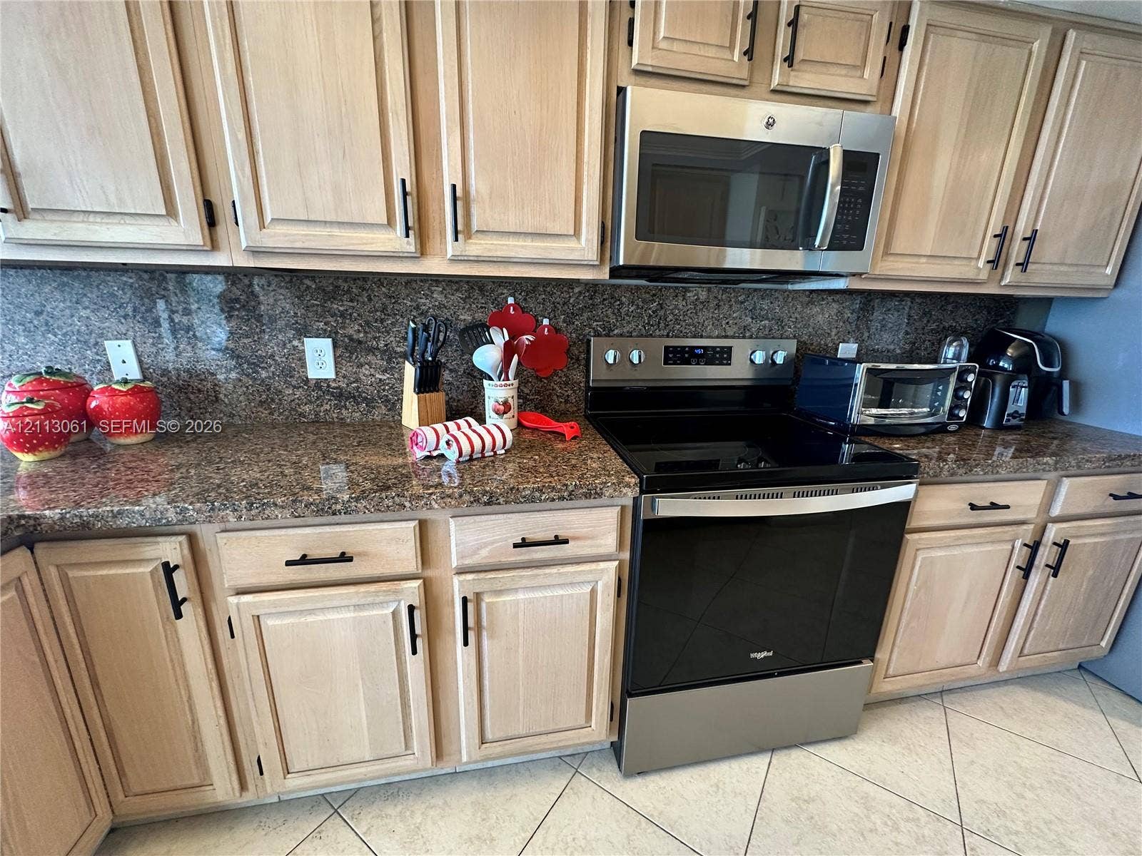 Kitchen featuring natural-finish wood cabinetry, stone countertops, coordinating stone backsplash, and stainless steel appliances