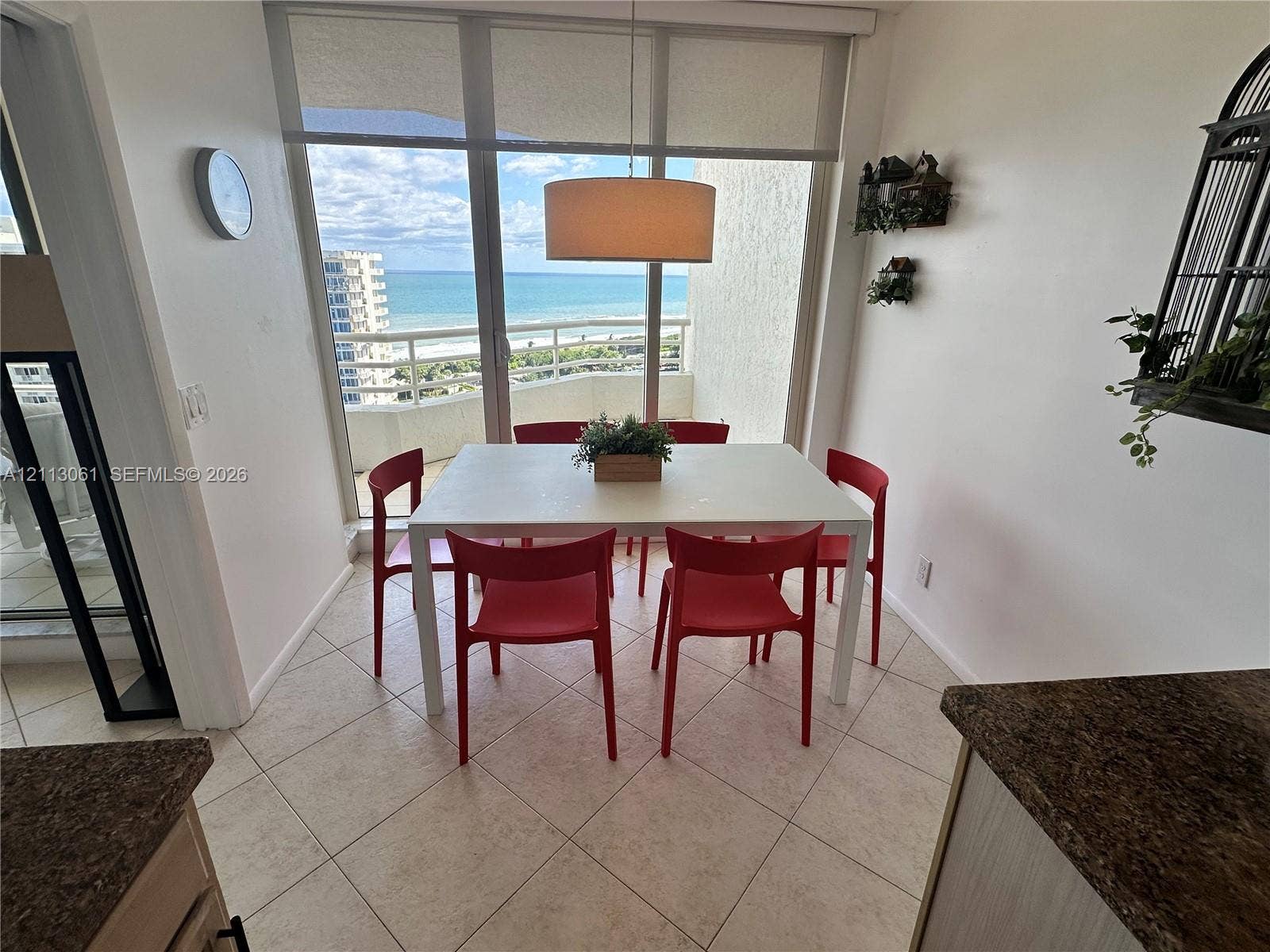 Floor-to-ceiling windows featuring ocean scenery, tile flooring, and a drum pendant light fixture