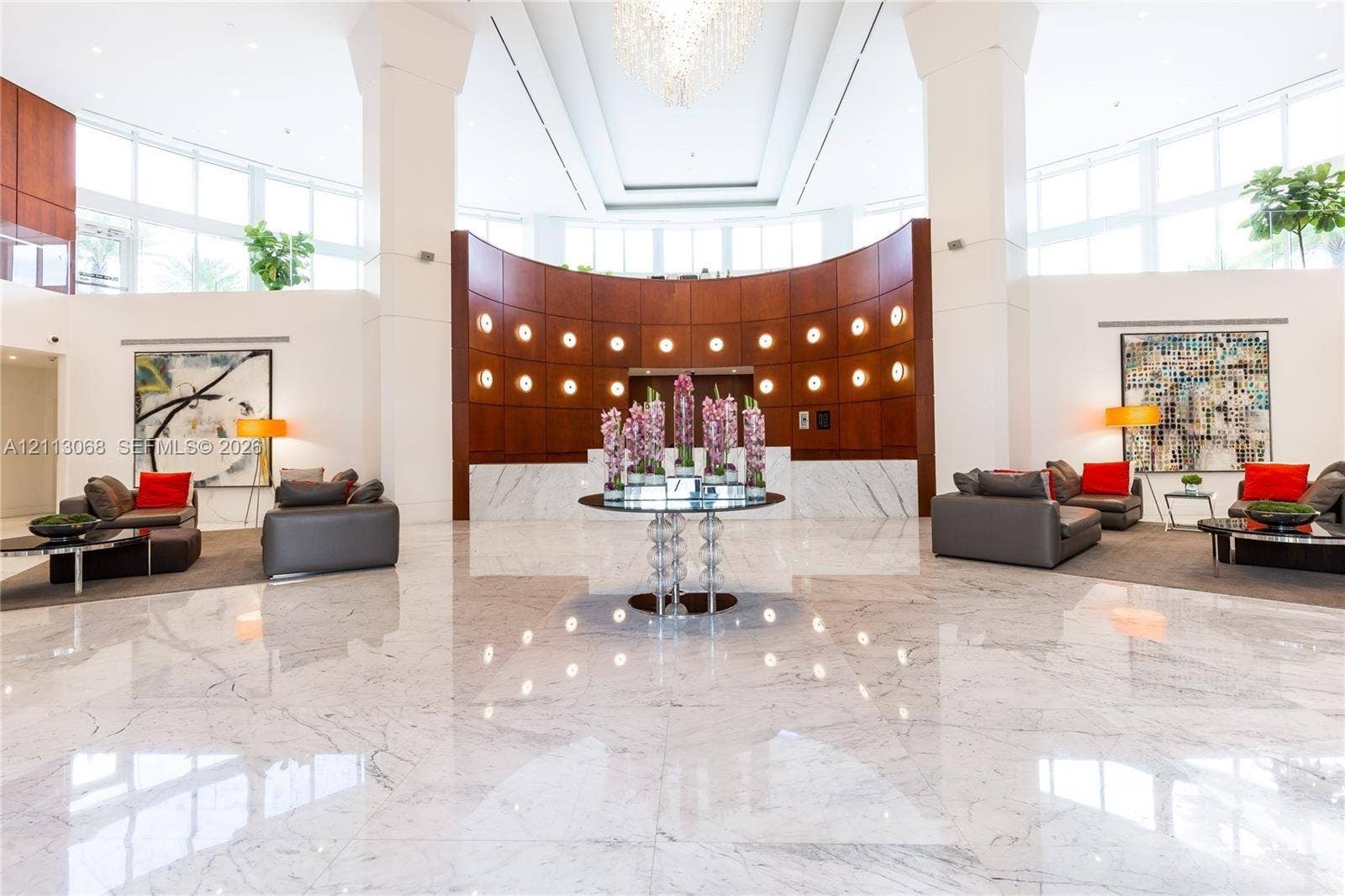 19111 Collins Avenue, #1007, Sunny Isles Beach, FL 33160 Grand lobby featuring polished stone flooring, vaulted ceilings, curved wood-paneled wall, recessed circular lighting, and large-scale windows