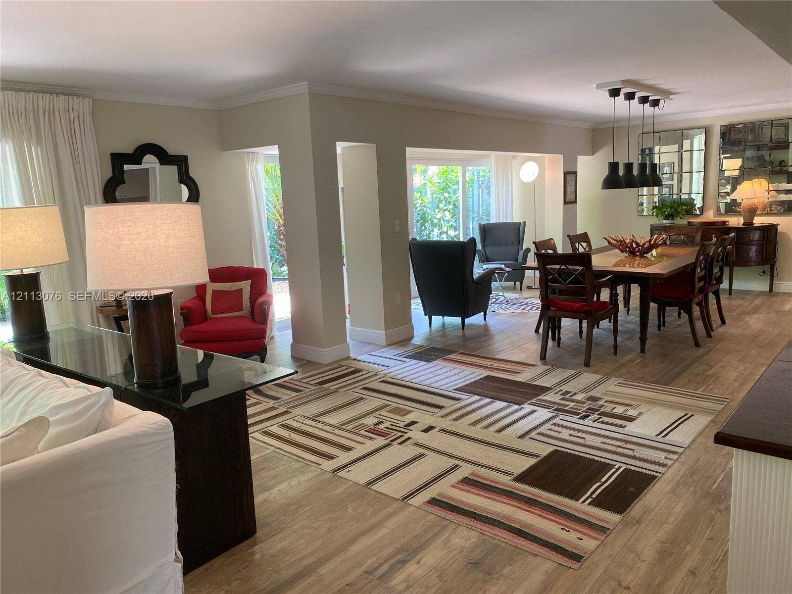 Open-concept interior featuring wood-finish flooring, crown molding, and a multi-pendant light fixture