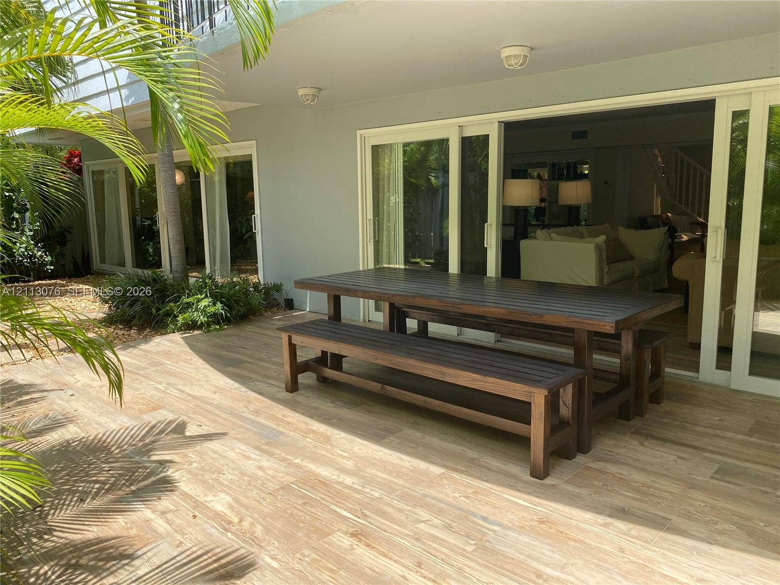 Covered patio featuring wood-finish tile flooring, multiple sliding glass door sets, and recessed lighting