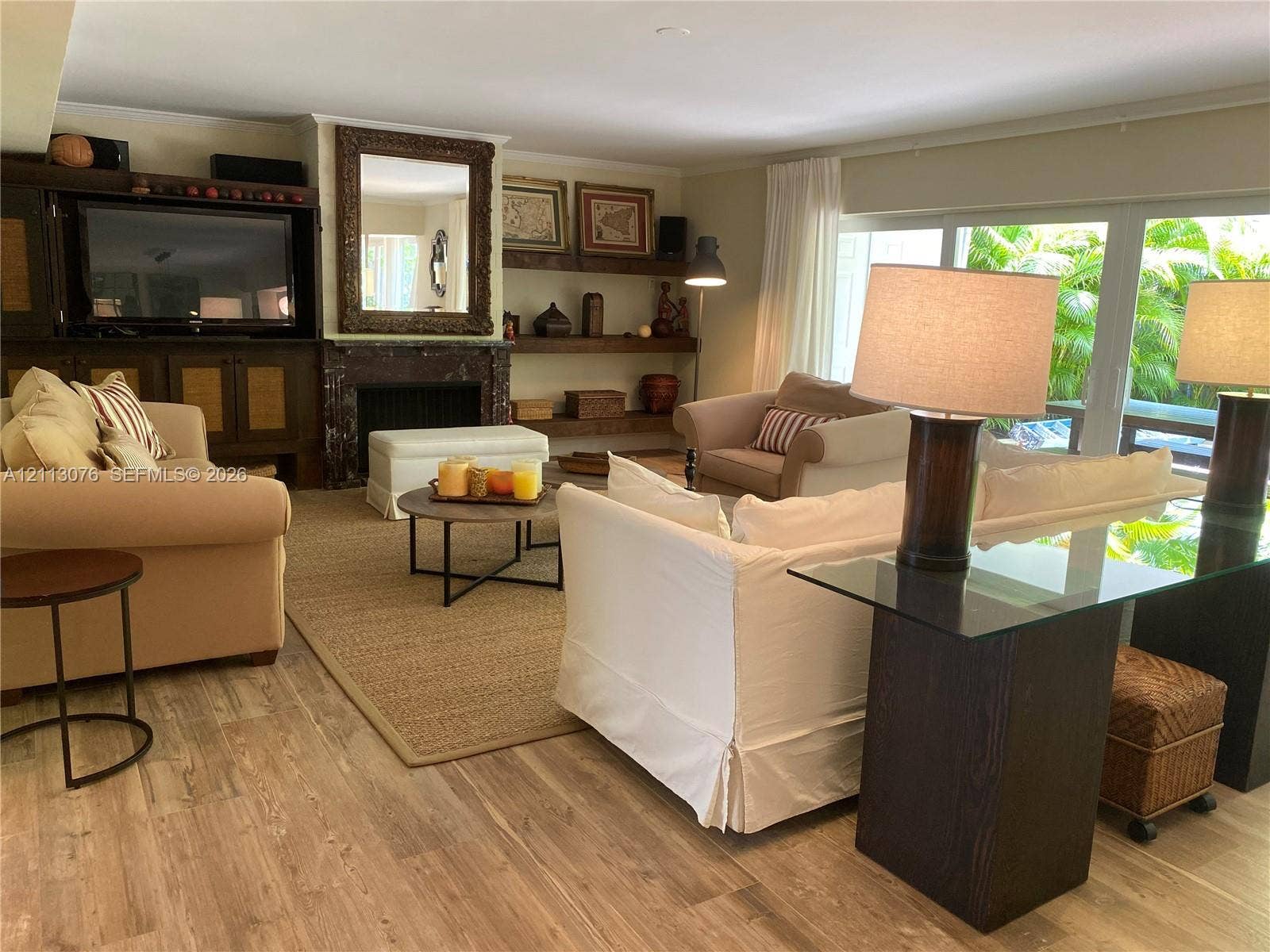 Living area featuring wood-finish flooring, a fireplace with dark stone surround, custom built-in cabinetry, floating wooden shelves, and sliding glass doors