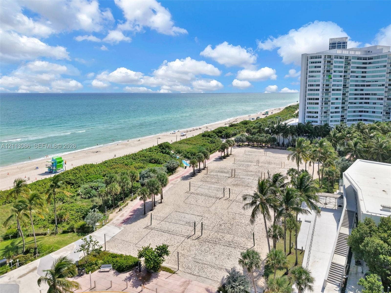7135 Collins Avenue, #1632, Miami Beach, FL 33141 Direct oceanfront positioning featuring a sandy beach, mature palm trees, multi-court athletic sand surface, and paved pedestrian pathways